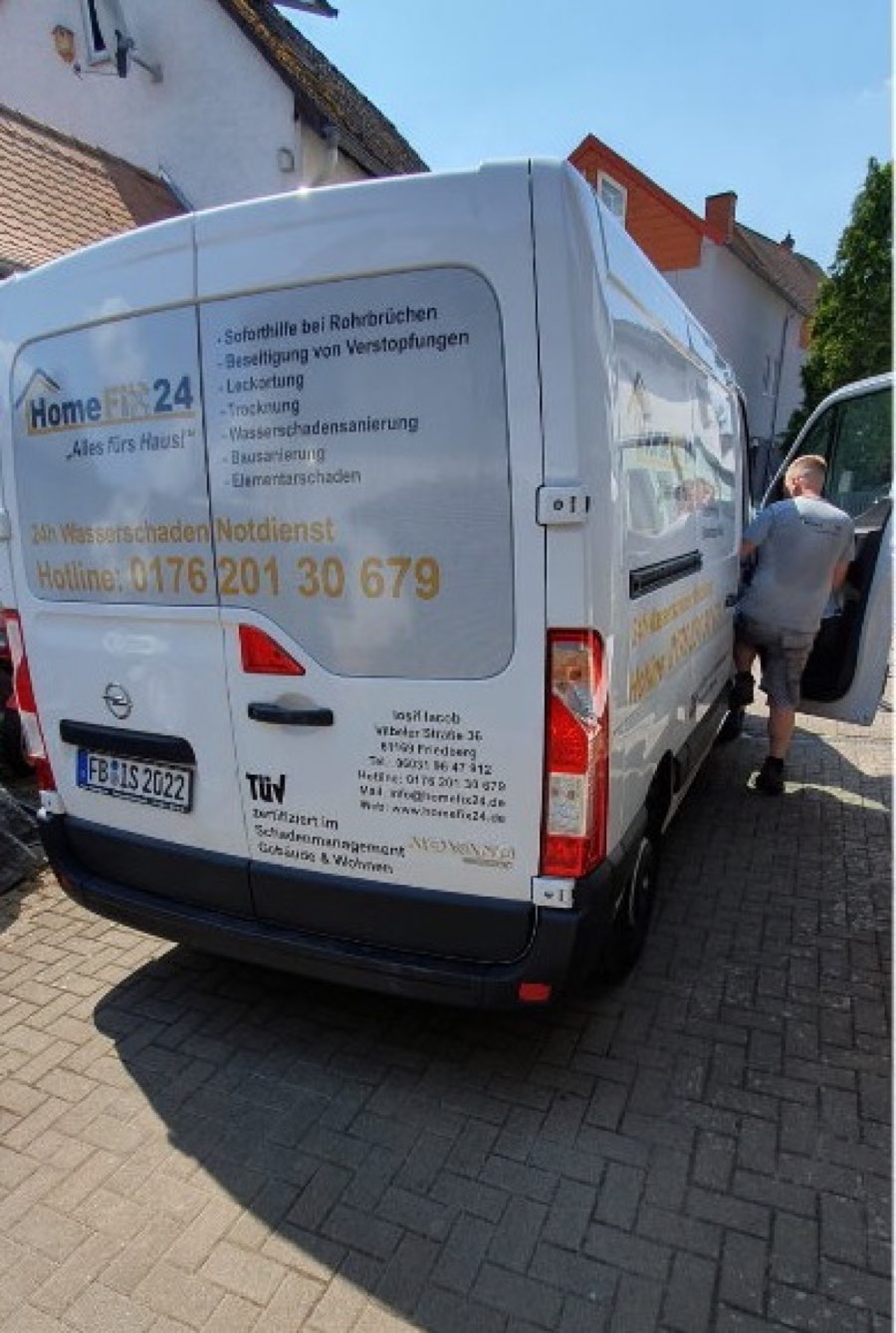 Beschriftetes Einsatzfahrzeug von HomeFix24 mit Notdienstnummer, ein Mitarbeiter belädt es