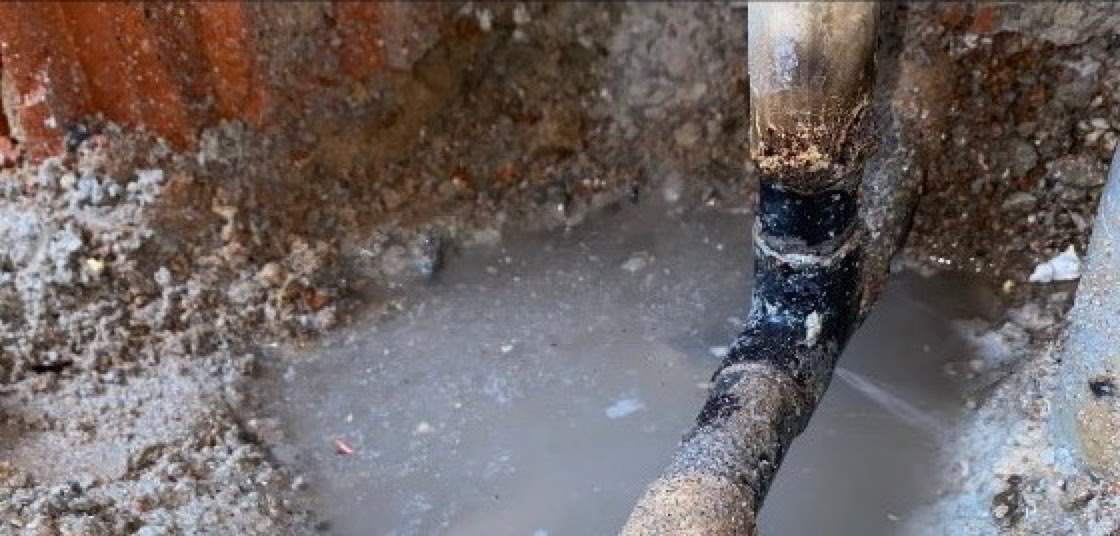 Rohrbruch-Notdienst Büdingen: freigelegte Leitung im Graben, das ausgetretene Wasser steht bereits in der Baugrube