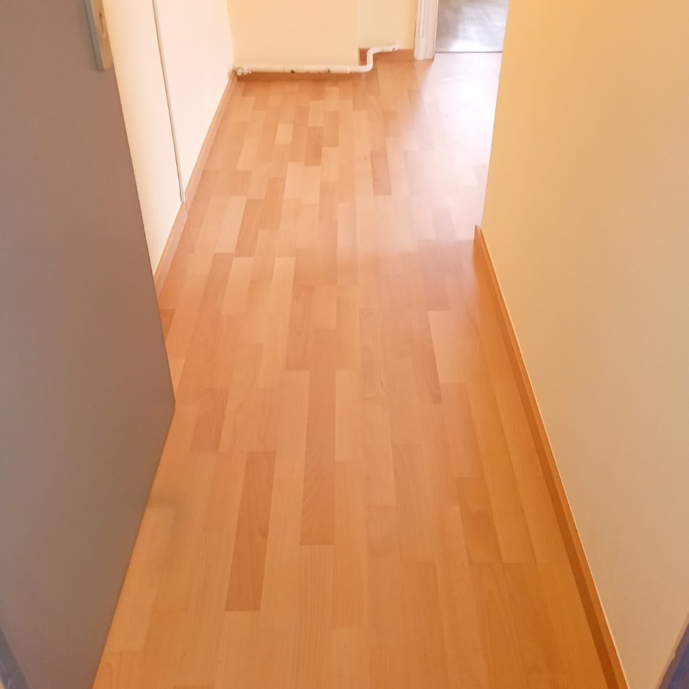 Fertiger Flur mit neu verlegtem Laminatboden in Buchenoptik und neuen Sockelleisten
