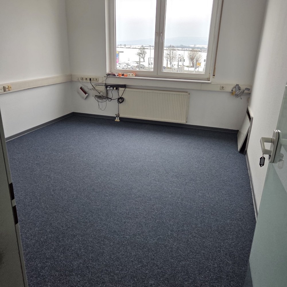 Dasselbe Büro fertig renoviert: frisch gestrichene Wände, leerer Raum, gereinigter Teppichboden