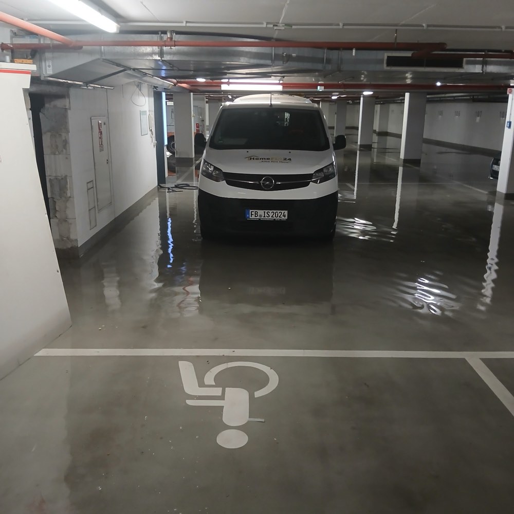 Überflutete Tiefgarage: Wasser steht flächig zwischen den Stellplätzen, davor ein Fahrzeug von HomeFix24
