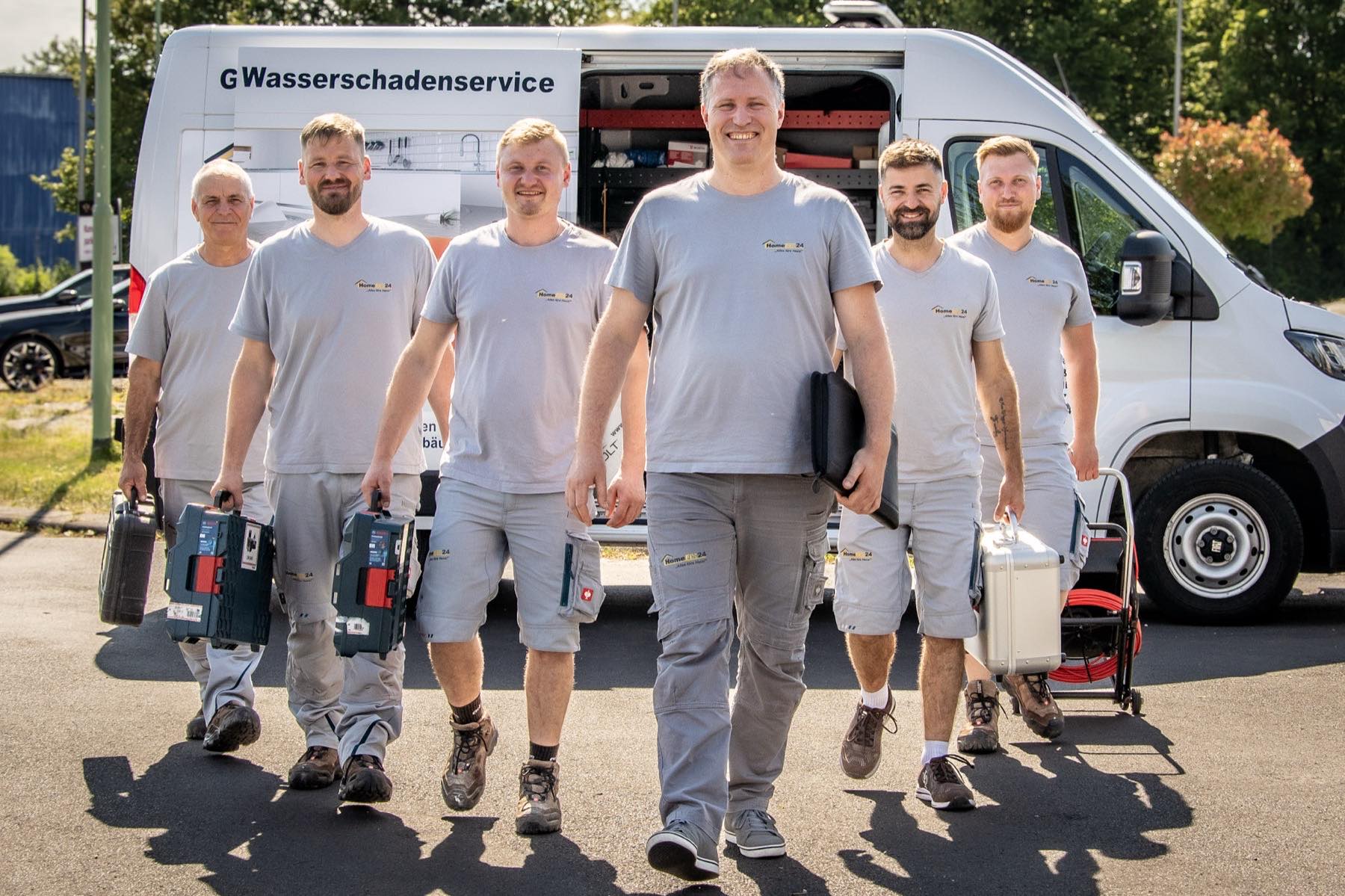Das HomeFix24-Team mit Werkzeugkoffern vor dem Einsatzfahrzeug